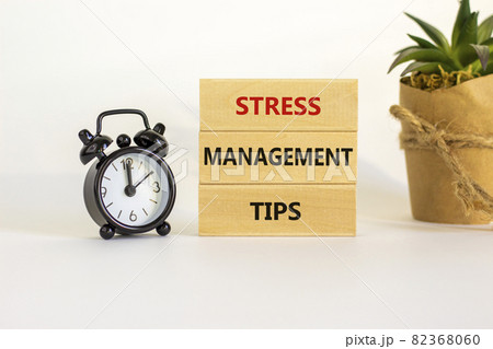 Stress management tips symbol. Wooden blocks with words 'Stress management tips'. Beautiful white background. Black alarm clock. Psychological, business and stress management tips concept. Copy space. Stress management tips symbol. Wooden blocks with words 'Stress management tips'. Beautiful white background. Black alarm clock. Psychological, business and stress management tips concept. Copy space. 82368060