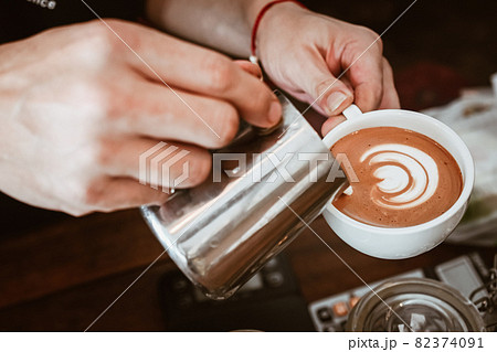 Barista pouring steamed milk to hot coffee to making latte art. A latte is a coffee drink made with espresso and steamed milk. Barista pouring steamed milk to hot coffee to making latte art. A latte is a coffee drink made with espresso and steamed milk. 82374091