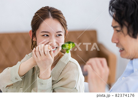 ブロッコリーを食べ飽きている男性と食べさせようとする女性 82374176