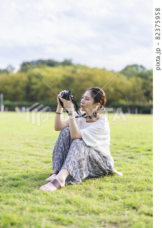 公園で写真を撮るカメラ女子 82375958