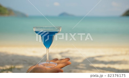 Man hands shake blue cocktails in glasses on beach 82376175