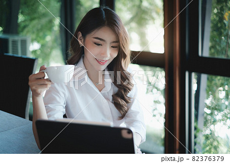 Image of beautiful business woman holds a cup of coffee and checks her email before going to work 82376379
