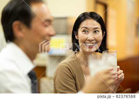 楽しく居酒屋でお酒を飲む中高年の夫婦 82376568