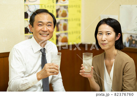楽しく居酒屋でお酒を飲む中高年の夫婦 82376760