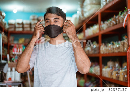 small business owner wearing face mask in front of his shop 82377137