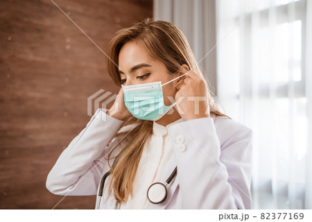 woman doctor wearing medical mask standing looking at camera woman doctor wearing medical mask standing looking at camera 82377169