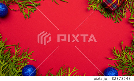 Christmas or New Year red background, framed by a Christmas tree, seasonal decorations, space for text, top view 82378548