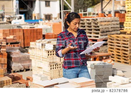 Woman manager keeps records of building materials in the open area of construction store 82378786