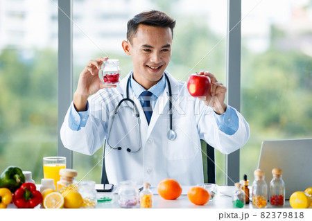 Male nutritionist with fruit and pills in medical office Male nutritionist with fruit and pills in medical office 82379818