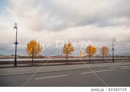 Dramatic view of the autumn city. Yellow autumn trees on the granite embankment in St. Petersburg. Dramatic view of the autumn city. Yellow autumn trees on the granite embankment in St. Petersburg. 82383720