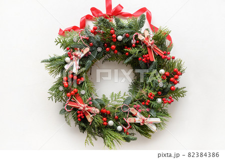 Christmas wreath of fresh natural spruce branch with red holly berries and decoration. New Year. Xmas holiday. 82384386