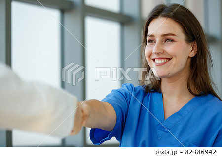 Woman Caucasian patient smile look comfortable and handshaking with a doctor. Focus to woman patient in an examination room at the hospital on morning day with light. 82386942