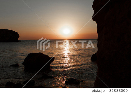 waves wash the rocky shore of the sea. Sunset. Reflection in the water of the bridge and rays 82388009