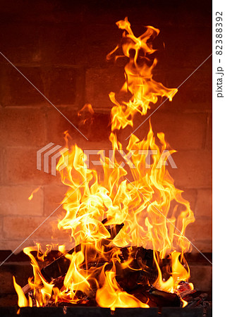 Orange flame from burning firewood in a brick grill. Close-up, selective focus 82388392
