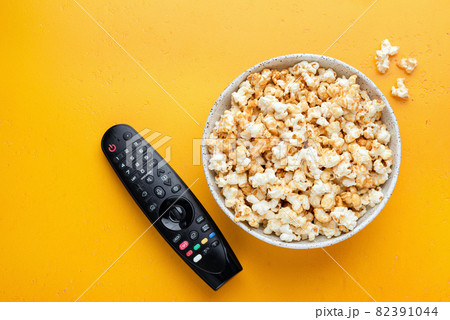 Bowl of popcorn and TV remote control Bowl of popcorn and TV remote control 82391044