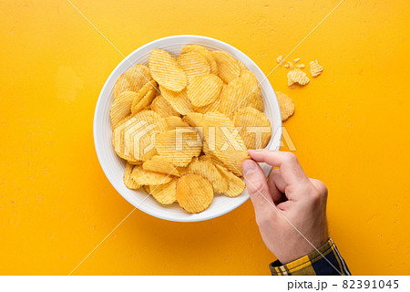 Spicy potato crisps in a bowl on yellow background 82391045