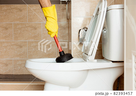Using a device to fix a clogged toilet bowl. 82393457