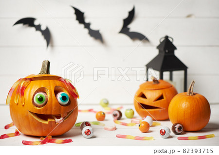 Kind smiling Halloween Pumpkin with candy eyes, teeth and hair of gelatin worms 82393715