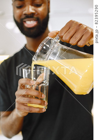 African-american man in a kitchen pouring a juice African-american man in a kitchen pouring a juice 82395290