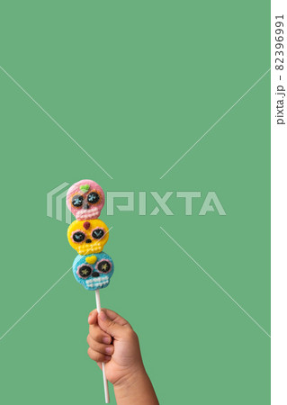 Kid hand holding candy skull lollipop Kid hand holding candy skull lollipop 82396991