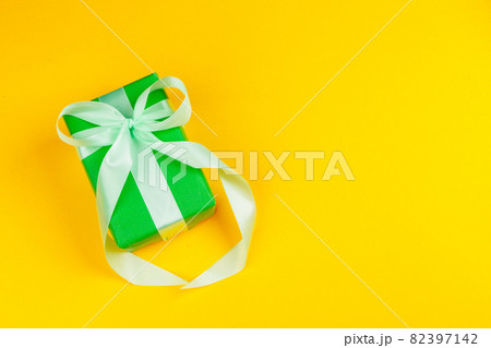 Decorated colored present on yellow background flatlay Decorated colored present on yellow background flatlay 82397142