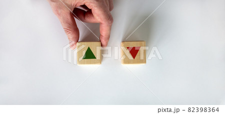 Hand making a choice between two cubes on white background. Wooden cubes changes the direction of an arrow symbolizing that the interest rates are going down or vice versa . Business concept. Copy 82398364