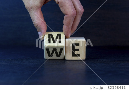 Me or we. Hand turns a wooden cube with me or we words on beautiful dark wooden background, copy space. Psychological and me or we concept. Me or we. Hand turns a wooden cube with me or we words on beautiful dark wooden background, copy space. Psychological and me or we concept. 82398411