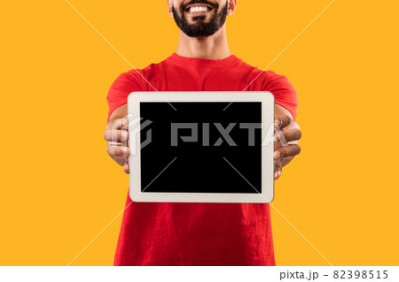Delivery Guy Showing Digital Tablet Screen Over Yellow Background, Cropped 82398515
