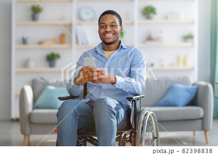 Praplegic black man in wheelchair using smartphone, browsing internet or watching video at home Praplegic black man in wheelchair using smartphone, browsing internet or watching video at home 82398838