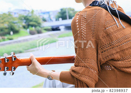 河原でアコギを弾く女の子 82398937