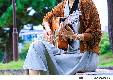 ベンチに座りアコースティックギターを弾く女性の写真素材 3943