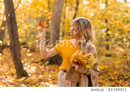 Portrait of beautiful young woman walking outdoors in autumn nature. Fall season and stylish girl concept. 82399911