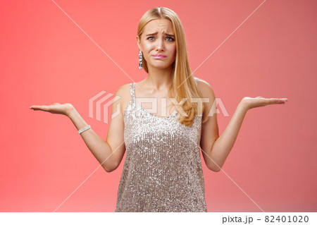 Nervous unsure doubtful cute blond woman struggle make decision shrugging pointing sideways frowning upset standing insecure feel pressure cannot decide choice make, frustrated red background 82401020