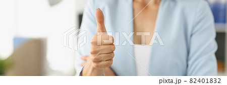 Businesswoman in suit holds thumbs up in office 82401832