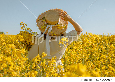 woman standing in rapeseed field rear view from behind woman standing in rapeseed field rear view from behind 82402207