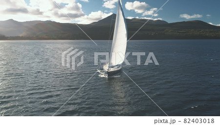 Luxury yacht race at sun light aerial. Yachting on serene seascape at open sea. Boat with white sail Luxury yacht race at sun light aerial. Yachting on serene seascape at open sea. Boat with white sail 82403018