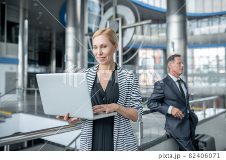 Woman looking at laptop and man with suitcase Woman looking at laptop and man with suitcase 82406071