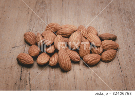Almonds are placed on the wooden floor at the center of the image, copy space. 82406768