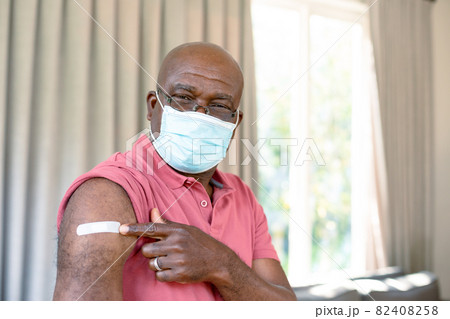 Senior african american man in face mask showing plaster after vaccination Senior african american man in face mask showing plaster after vaccination 82408258