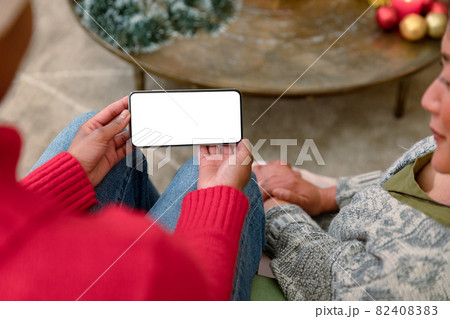 Two diverse female friends using smartphone with copy space at christmas time 82408383
