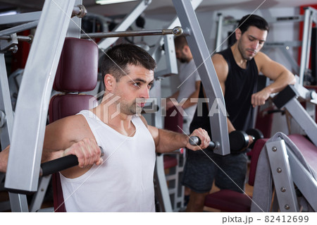 Guy training on fitness machine in gym Guy training on fitness machine in gym 82412699