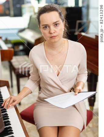 Female assistant or customer at piano music store Female assistant or customer at piano music store 82413296