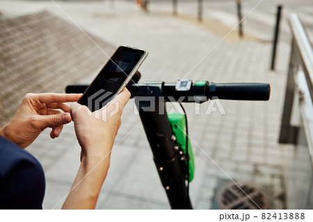 Woman unlock electric scooter for rent with a smartphone application Woman unlock electric scooter for rent with a smartphone application 82413888