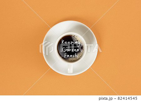 Top view of cup of black coffee and Keeping coffee fresh lettering isolated on orange background 82414545