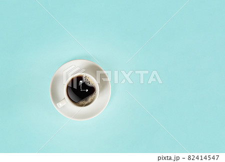 Arrows of a clock in a cup of coffee on blue background. View from above. 82414547
