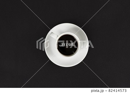 Coffee in white cup with a lettering 77 charge on black slate background 82414573
