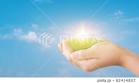 Hand holding green grass field over blue sky background. Hand holding green grass field over blue sky background. 82414837