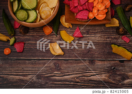 Healthy homemade vegetable chips on wooden table. 82415005
