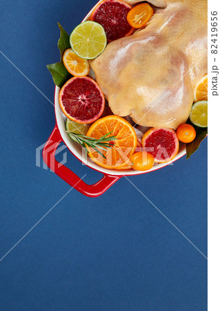 Herb and citrus oven roasted chicken. Whole chicken in roasting tin with lemon and herbs ready for the oven. Top view, blank space 82419656