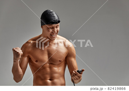 Excited swimer with stopwatch standing on gray background. New record. Motivation, advertising banner, place for text 82419866